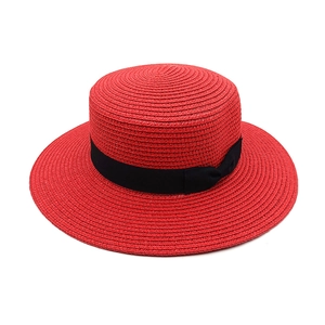 Detail of red straw sun hat with black ribbon band and elegant side bow decoration
