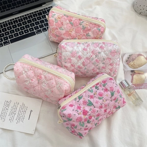 Detail of floral quilted cotton makeup bags with zippers and elegant pearl handle chains