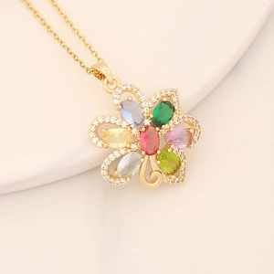 Golden flower pendant necklace with colorful zircons on a soft stone background