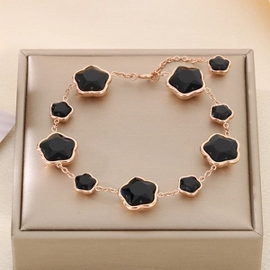 Détail du bracelet trèfle en or rose avec motifs de fleurs noires dans un écrin de luxe