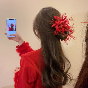 Detail of red Manjushaka flower hair clip worn by a model in a traditional style
