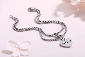 Detail view of heart charm with MOM engraving on double-layer pearl chain bracelet