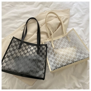Flat lay of black and beige transparent mesh tote bags with all-over M-letter pattern