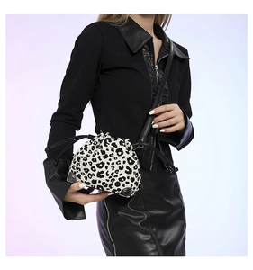 Detail of leopard print bucket bag with drawstring closure shown on shoulder