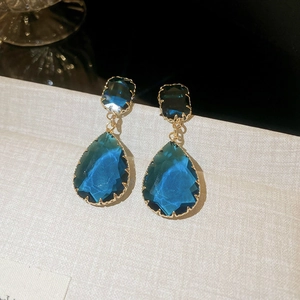 Close-up of luxury dark blue teardrop and square zircon drop earrings with gold metal claws