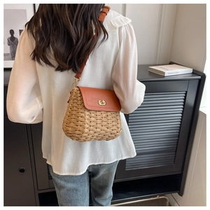 Close-up of handmade straw crossbody bag with brown leather flap and golden twist lock