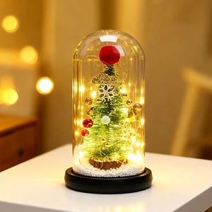 Close-up of a mini Christmas tree and snow inside a glass dome with LED lights
