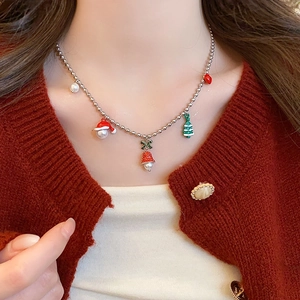 Close-up of Christmas necklace with bell, tree, and heart charms on a red sweater