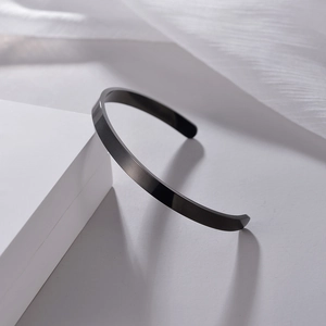 Bracelet jonc ouvert en forme de C en acier inoxydable noir sur tissu blanc texturé