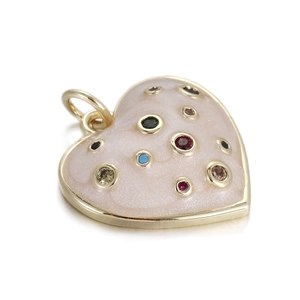 Macro detail of heart-shaped gold pendant with pink enamel and colorful gemstones