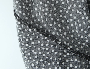 Makro-Detail von hochwertiger Overlock-Naht und weißem Polka-Dot-Druck auf schwarzem Stoff