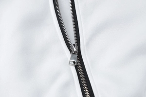 Macro shot of silver metal zipper on white knitted fabric showing high-quality texture
