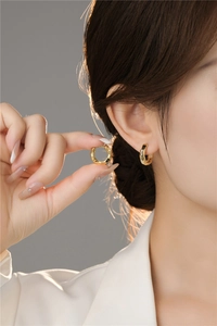 Detailed close-up of golden irregular textured hoop earrings worn by a model