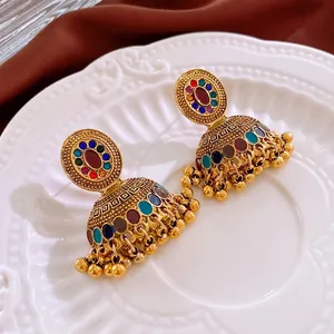 Orecchini Jhumka vintage dorati con gemme colorate e dettagli nappe su ceramica bianca