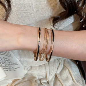 Close-up of gold leopard print bangles and twisted rope bracelets on woman's wrist