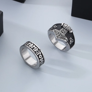 Close-up of Norse Viking rune ring and silver Thor hammer signet ring on grey surface