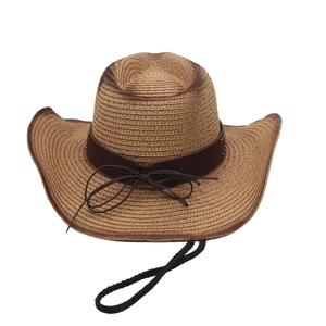 Close-up of woven straw cowboy hat with decorative brown belt and adjustable chin cord