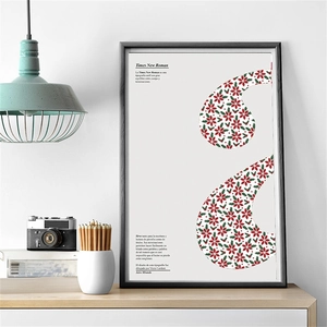 Close-up of modern Christmas floral comma poster in a black frame on a wooden desk
