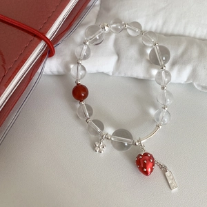 Detail of beaded strawberry bracelet with glass beads and silver flower pendant