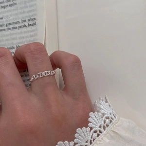 Close-up of a silver mariner link chain ring worn on finger with a vintage background