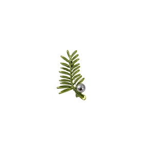 Detail of green leaf brooch featuring a grey pearl and textured metal finish