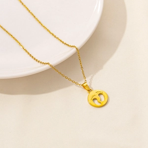 Macro shot of gold stainless steel necklace with hollow round footprint pendant