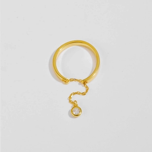 Macro view of gold chain ring featuring a dangling round clear zircon pendant detail