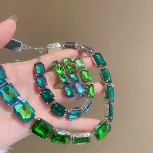 Detail of luxury square rhinestone jewelry set with green and purple stones in hand