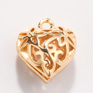 Detailed macro view of heart-shaped hollow golden charm with intricate floral patterns