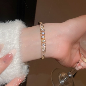 Close-up of gold-plated bangle with rows of clear cubic zirconia worn by a model