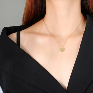 Close-up of a gold necklace featuring a round pendant with a Chinese Fu character