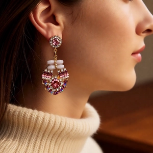 Close-up of vintage gold earrings with pink crystals on model in cozy sweater