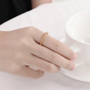 Bague perlée dorée minimaliste pour femme portée sur le doigt dans une scène de café