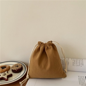 Brown canvas drawstring storage bag with cotton rope closure in a cozy home setting