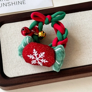 Detail of a festive Christmas scrunchie with red and green bells and plush snowflake charm