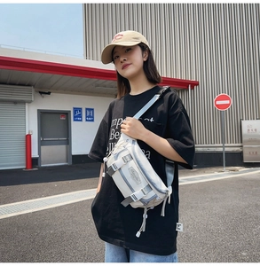 Outdoor shot of cream nylon crossbody chest bag with adjustable gray strap and multi-zipper pockets