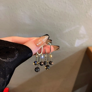 Gros plan de boucles d'oreilles géométriques dorées avec boules strass noir et chaînes
