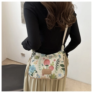 Detail of floral tapestry tote with leather trim and branded patch on textured fabric