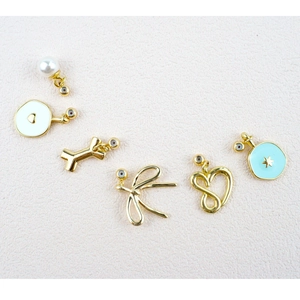 Detailed close-up of mixed gold charms featuring bow, bone, heart, and enamel star designs