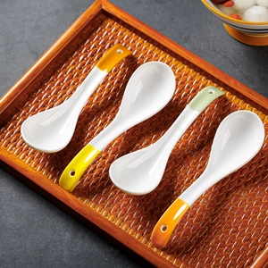 Japanese style blue and white ceramic soup spoons with colorful handles on bamboo tray
