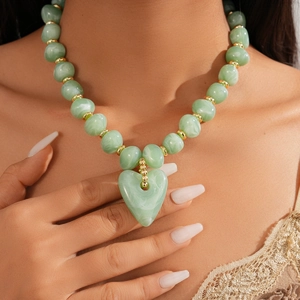 Close-up of green marble texture acrylic beads and heart pendant on a gold tone necklace