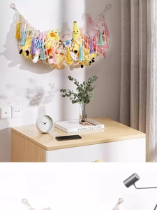 Detail of hand-woven cotton macrame toy hammock with vibrant colorful tassels on wall