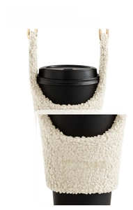 Close-up of fluffy cream lamb wool coffee sleeve with a handle and custom gold hardware