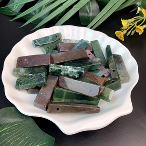 Natural rectangular stone crystal pendants in deep green and brown on a shell tray