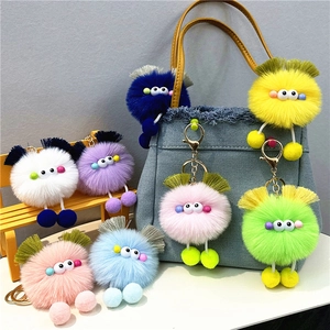 Close-up of colorful plush monster keychains in various colors on a denim handbag