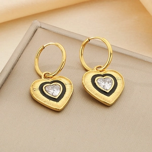 Close-up of heart earrings with black enamel, brushed gold texture and zircon inlay