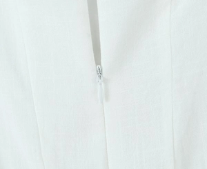 Close-up of invisible back zipper on white dress with ruffled hem and clean stitching