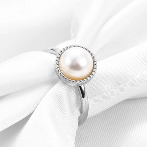 Macro shot of 10mm white pearl ring with beaded silver stainless steel edge on silk