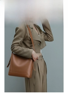 Brown leather bucket bag styled with a khaki suit for a modern professional commuter look
