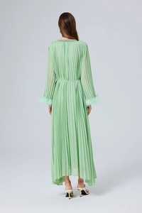 Détail d'une robe maxi plissée vert menthe avec poignets en plumes et col perlé